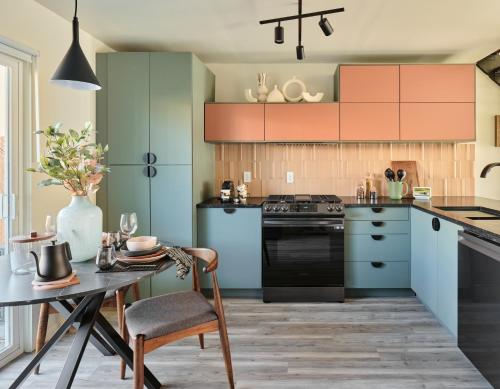 a kitchen with blue and green cabinets and a table at Midcentury Couples Designer Loft - Casa Tuya in Austin