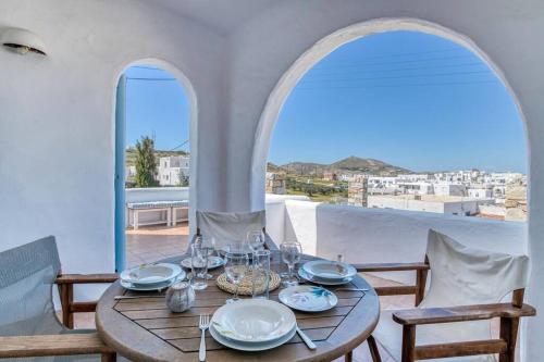 a wooden table with plates and glasses on a balcony at Thálassa House - Walking distance to Naoussa in Naousa