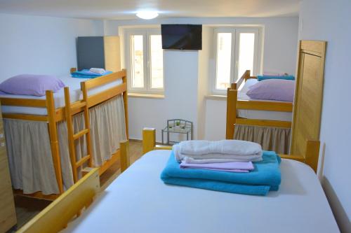 a room with two bunk beds and a table with towels at Montenegro Backpackers Home Budva in Budva