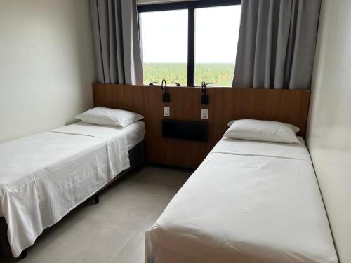 two beds in a room with a window at Salinas Premium Resort 2Q in Salinópolis