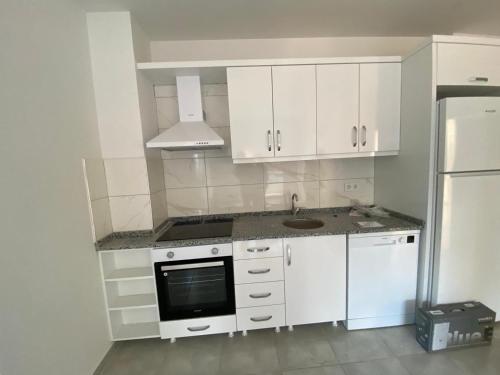 a kitchen with white cabinets and a sink and a refrigerator at Avsallar Star Residence in Avsallar