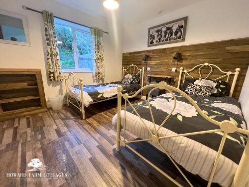 2 łóżka w pokoju z drewnianą podłogą w obiekcie Howard Farm Holiday Cottages w mieście Bude