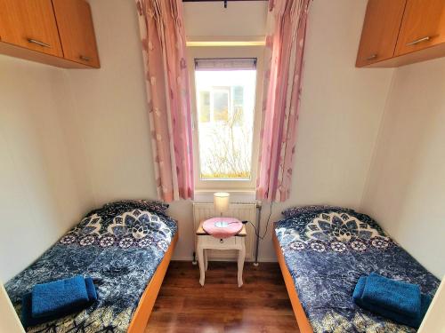 een kleine kamer met 2 bedden en een raam bij De Parel van Zeeland met jacuzzi en sauna in Sint Annaland