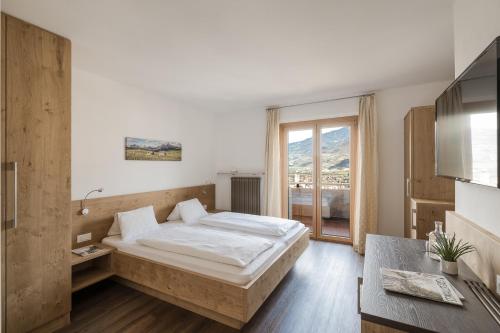 a bedroom with a bed and a large window at Panorama Hotel Garni Bühlerhof in Lana