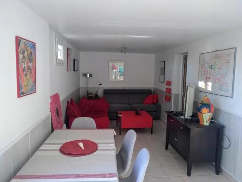 uma sala de estar com uma mesa e um sofá vermelho em LA MADRAGUE- 2P avec piscine privative em Saint-Cyr-sur-Mer