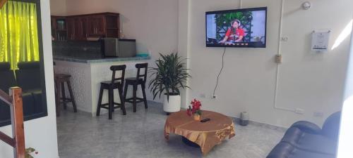 sala de estar con mesa y TV en la pared en cabaña 61santorini colombiano en Doradal