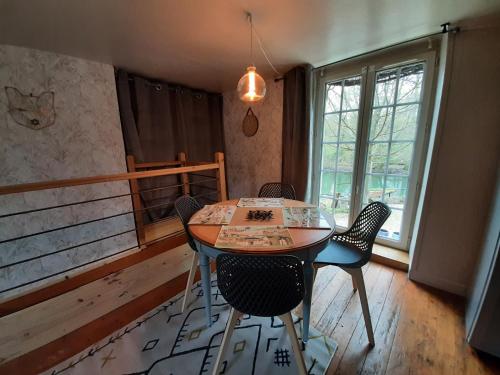 d'une salle à manger avec une table, des chaises et une fenêtre. dans l'établissement Dans moulin au bord de l'eau, Appartement chaleureux, à Saint-Pryvé-Saint-Mesmin