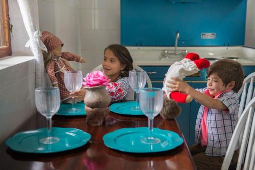 a boy and a girl are sitting at a table with glasses at Hotel Boutique Casa de Hacienda Su Merced in Puembo