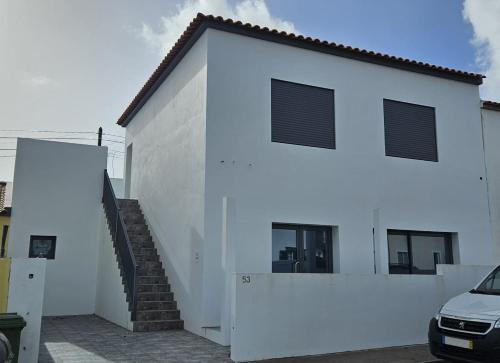 een wit gebouw met een trap naast een auto bij Casa da Relva in Ponta Delgada