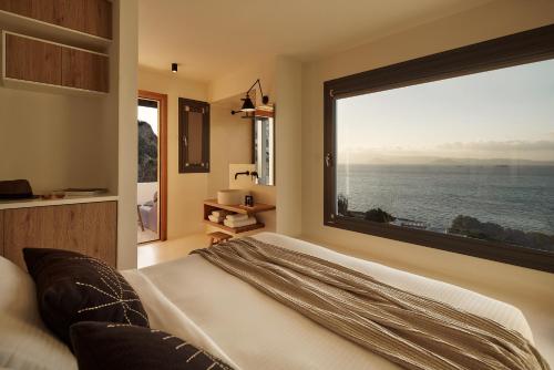 a bedroom with a large window with a view of the ocean at Naxea Villas I in Plaka