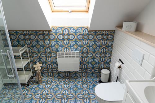 a bathroom with a toilet and a blue and white tiles at Rozmaryn - Komfortowy domek całoroczny na Kaszubach in Borowy Młyn