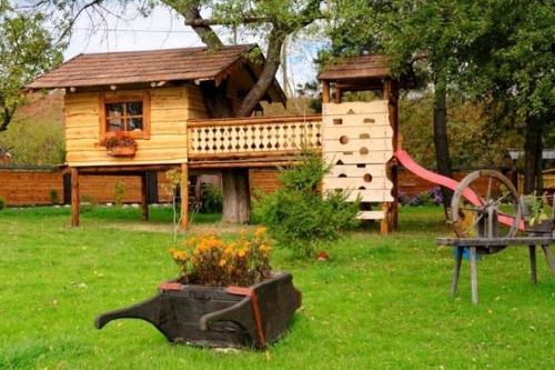a small wooden house with a playground and a garden at Chalupa Peter in Liptovský Michal