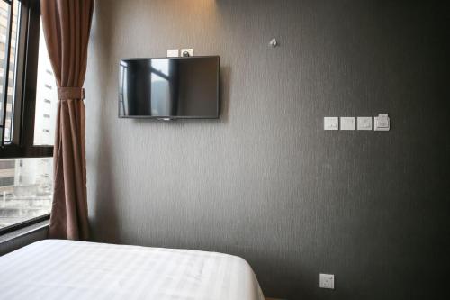 a bedroom with a bed and a tv on the wall at Hygge House in Hong Kong