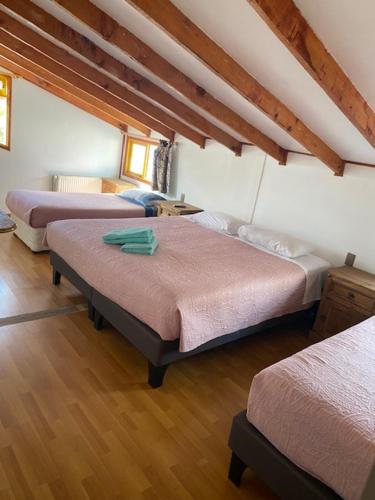 um quarto com três camas num quarto em Nikos II Adventure em Puerto Natales