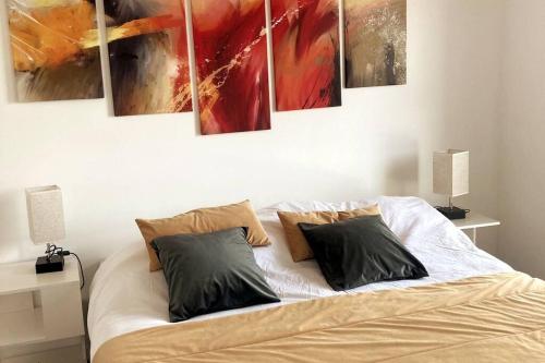 een slaapkamer met een bed met vier schilderijen aan de muur bij Les Mouettes au Vert in Sangatte