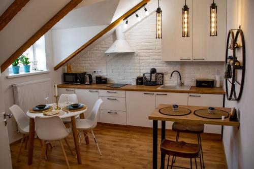 cocina con armarios blancos, mesa y sillas en Old Town Loft Apartments, en Kamianets-Podilskyi