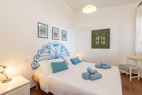 a bedroom with a white bed with blue pillows on it at Fronte Mare Pinus Village 76 in Santa Margherita di Pula