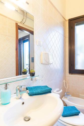 a bathroom with a sink and a mirror and a toilet at Fronte Mare Pinus Village 76 in Santa Margherita di Pula
