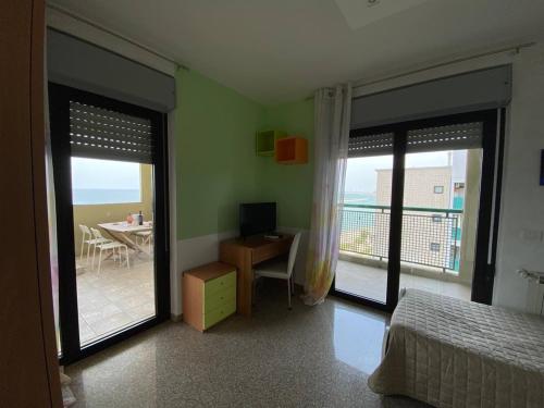 sypialnia z łóżkiem i biurkiem oraz balkon w obiekcie Fronte Mare w mieście Bari