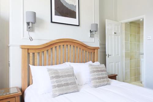 a bedroom with a white bed with two pillows at The Kendrick Exclusively for adults in Llandudno