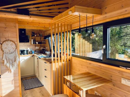 cocina con paredes de madera, mesa y ventana en The Grey Tiny en Chimay