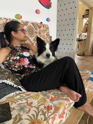 a woman sitting on a couch with a dog at Casa da Si Hostel in Ubatuba