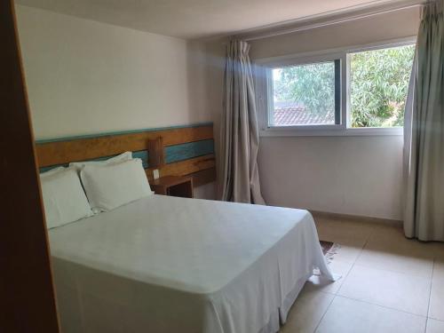 a bedroom with a white bed and a window at Ilha Deck Hotel in Ilhabela