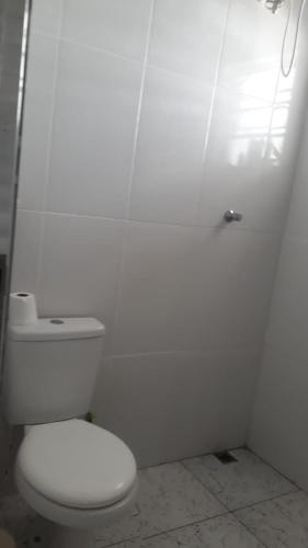 a white bathroom with a toilet and a white wall at Casa das Gaivotas in Itanhaém