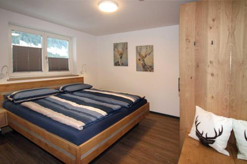 1 dormitorio con cama y ventana en alpenHIRSCH - Ferienwohnungen, en Hirschegg