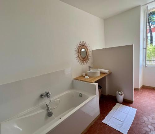 a white bathroom with a tub and a mirror at La Maison de Lola in Carpentras