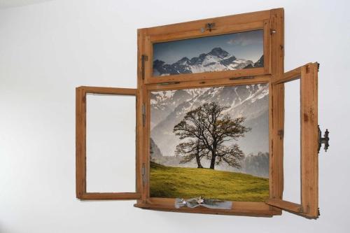a window with a picture of a tree at alpenHIRSCH - Ferienwohnungen in Hirschegg