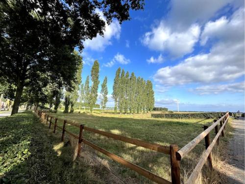 a wooden fence next to a field with trees at De Cordobahoeve in Tweede Exloërmond