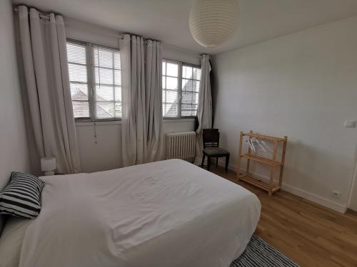1 Schlafzimmer mit einem weißen Bett und 2 Fenstern in der Unterkunft Les Embruns in Bréhal