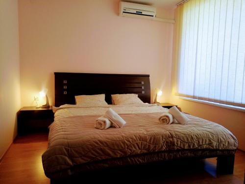 a bedroom with a large bed with two towels on it at Family Apartament Crown Pool&Sea - BastetBS in Sveti Vlas