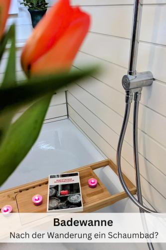 a vase with a flower next to a shower at Black Forest Stay - Apartment Hirschperle in Sasbachwalden
