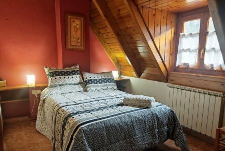 um quarto com uma cama grande num sótão em Alojamiento Rural Ostau Era Nheuada em Aubert
