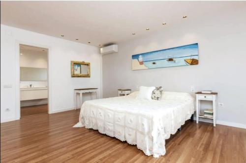 een witte slaapkamer met een bed en een schilderij aan de muur bij Paradise holidays in Barcelona in Alella