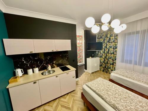 a room with two beds and a kitchen with a sink at Apartamenty Green in Stargard