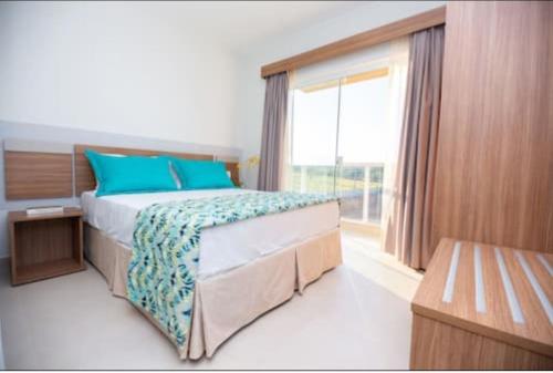 a bedroom with a bed with blue pillows and a window at Ilhas do Lago Eco Resort in Caldas Novas
