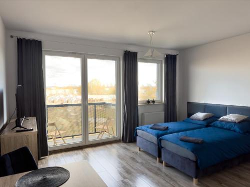 a bedroom with a blue bed and a large window at Apartament Nowa Cukrownia in Szczecin