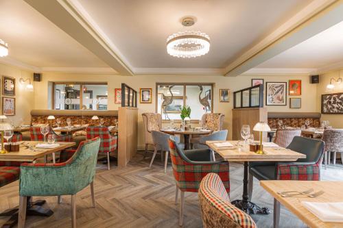 a restaurant with wooden tables and chairs at The Manor Coastal Hotel & Inn, Blakeney - The Coaching Inn Group in Blakeney