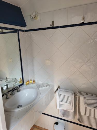 a white bathroom with a sink and a mirror at La Chouette de Camargue in Aigues-Mortes