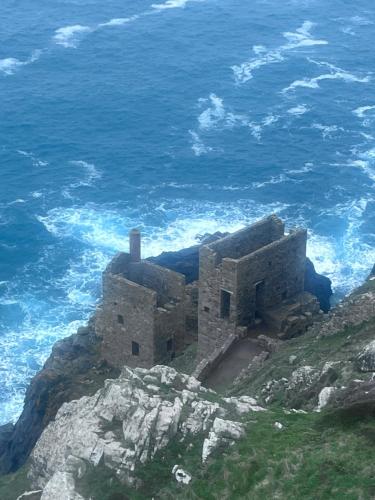 a building on top of a cliff next to the ocean at Gwens Garden bell tent in St. Just