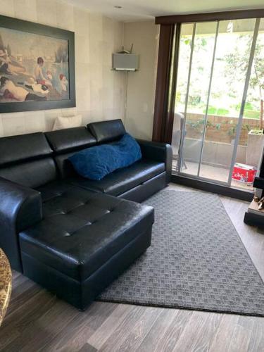sala de estar con sofá de cuero negro y mesa en Apto duplex amplia terraza, en Bogotá