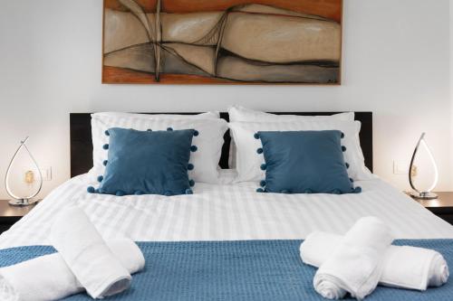 Maisonette near Heraklion Center Candia Maisonette في مدينة هيراكيلون: غرفة نوم مع سرير أبيض كبير مع وسائد زرقاء
