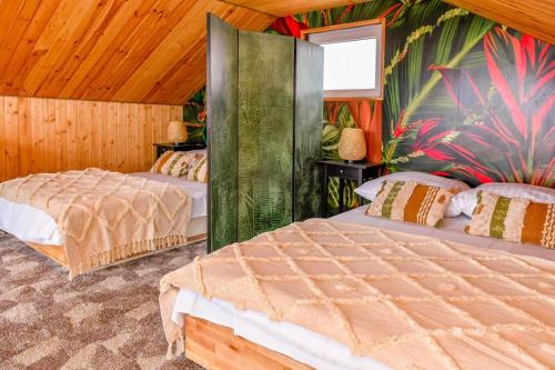 two beds in a room with wooden walls at Nini House Swietajno in Olecko