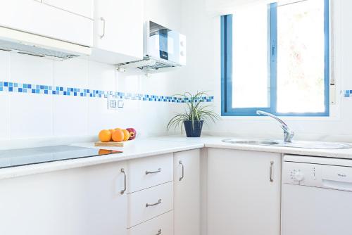 a white kitchen with a sink and oranges on the counter at Villa Congrio in Las Negras