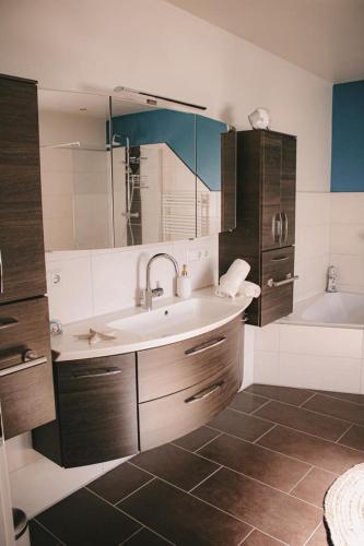 a bathroom with a sink and a bath tub at Maricas Meereszeiten Wellness in Midlum