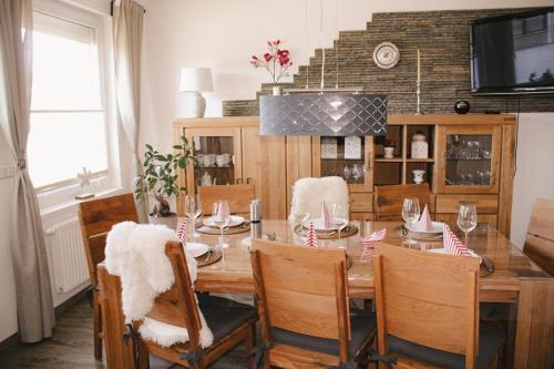 a dining room with a wooden table and chairs at Marica‘s Meereszeiten Wellness in Midlum