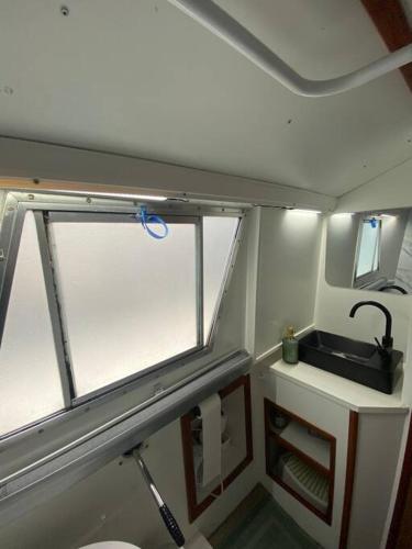 une petite salle de bain avec un lavabo et une fenêtre dans l'établissement Charmant bateau sur la Marne, à La Ferté-sous-Jouarre